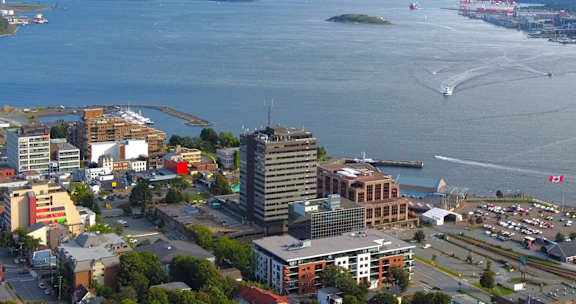 A cityscape with a large body of water and a ferry in the distance.