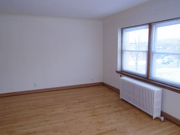 Floor Plan  an empty room with a wood floor and a radiator and two windows