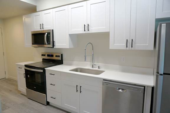 Floor Plan  A kitchen with white cabinets and stainless steel appliances.