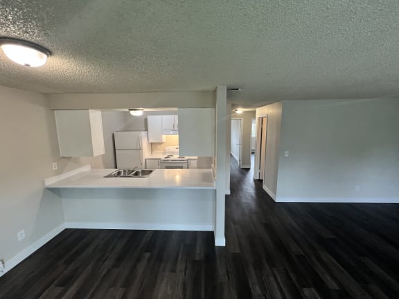 Floor Plan  a view of a kitchen and a living room with wood flooring and white cabinets