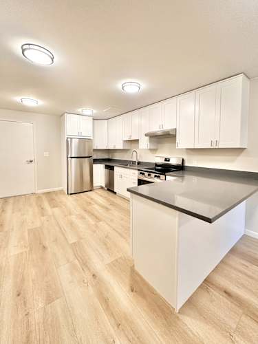 Floor Plan  A kitchen with white cabinets and a wooden floor.