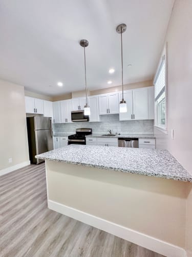 Floor Plan  a kitchen with white cabinets and a granite counter top
