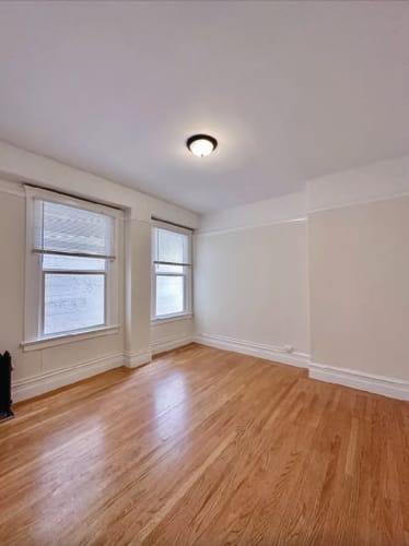 Floor Plan  an empty living room with a wooden floor and two windows