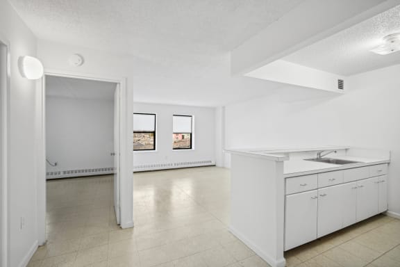 Floor Plan  the living room and kitchen of an apartment with white cabinets and a sink