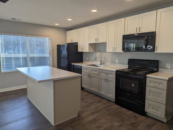 Floor Plan  a kitchen with white cabinets and black appliances