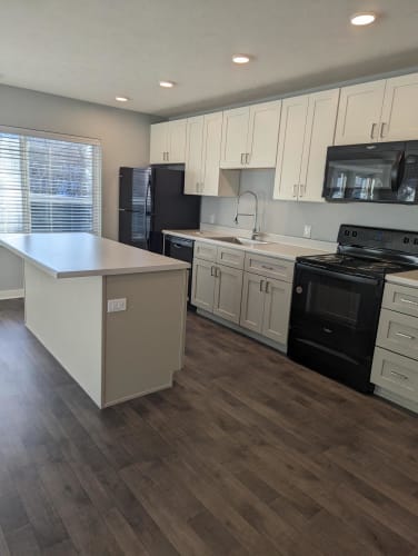Floor Plan  a kitchen with white cabinets and black appliances