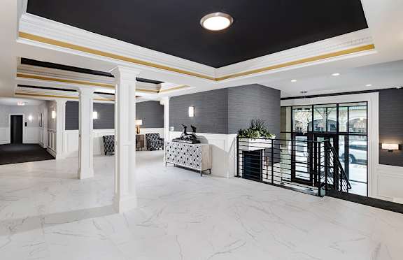 A spacious foyer with marble flooring and a black and white patterned sofa.