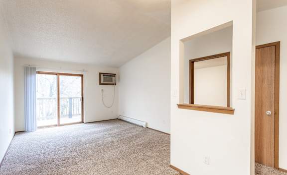 Floor Plan  A large, empty room with a carpeted floor and a window with blinds.
