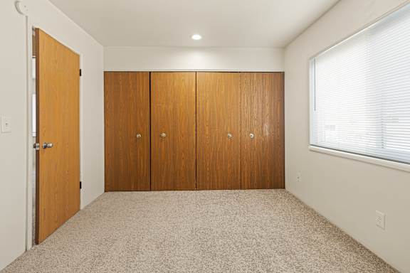 Floor Plan  A room with a carpeted floor and a set of wooden doors.