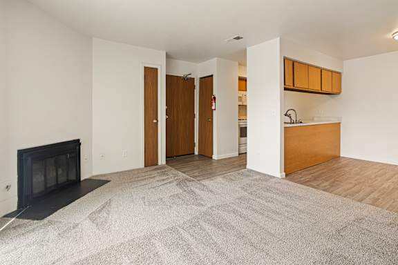 Floor Plan  A living room with a fireplace and a grey carpet.