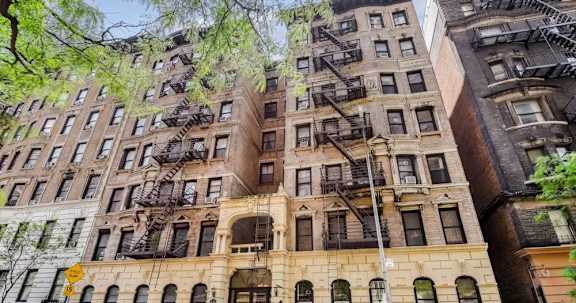 Floor Plan  A row of brown buildings with fire escapes on the side.