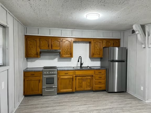 Floor Plan  view of a kitchen with a sink stove and fridge with wood cabinentry