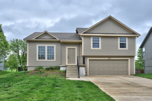 Floor Plan  a tan house with a driveway and a garage door