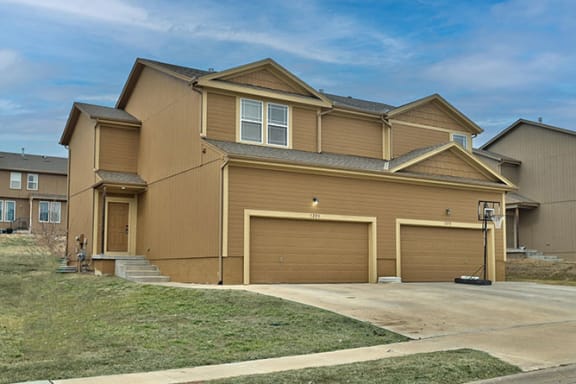 Floor Plan  a brown house with three garages and a blue sky
