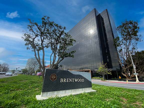 A modern glass building with a sign that reads "Brentwood" in front of it.
