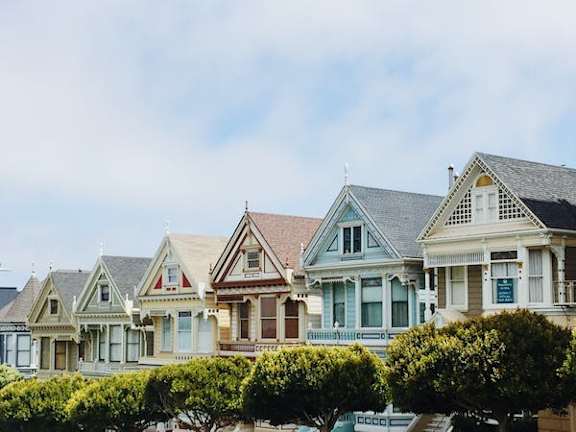 A row of Victorian style houses with green shutters.