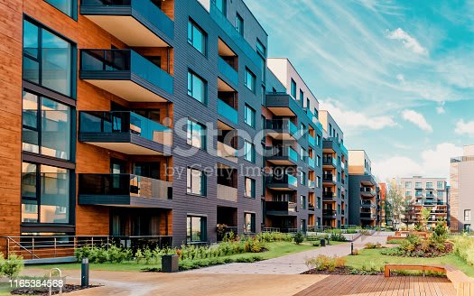 A modern apartment complex with balconies and a garden in front.