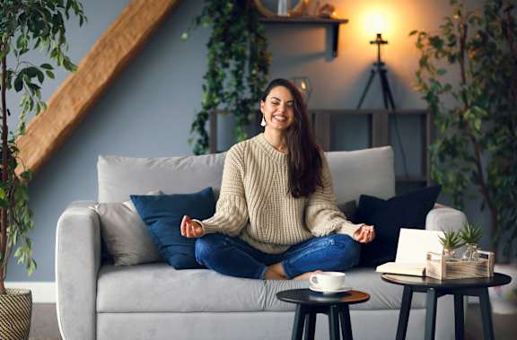 a woman sitting on a couch meditating in a living room