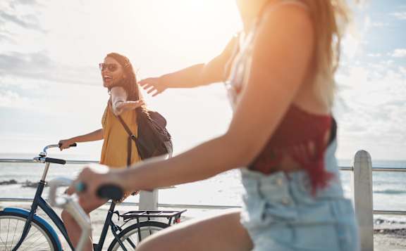 a man and a woman standing on the beach with their bikes