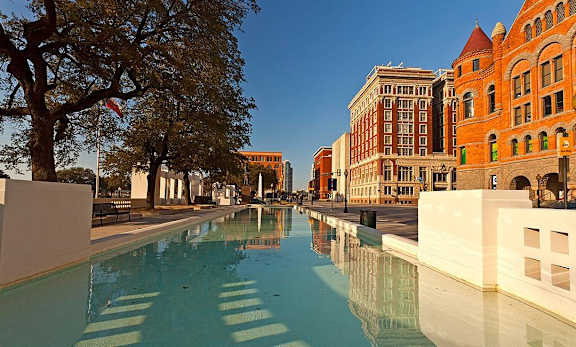 A long rectangular pool with a building in the background.