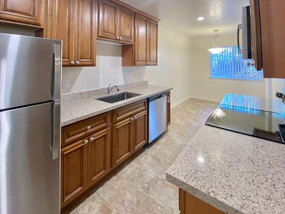 A kitchen with a stainless steel refrigerator and wooden cabinets.