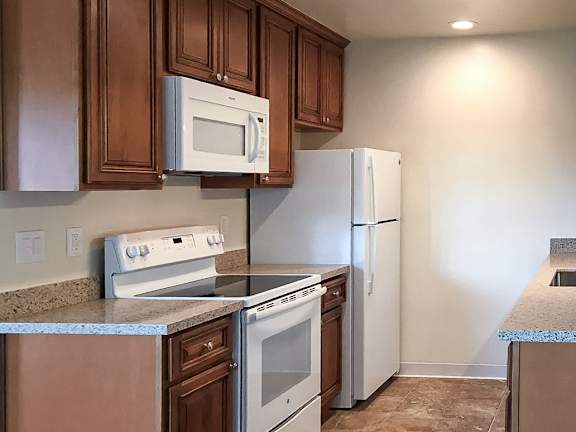 A kitchen with brown cabinets and white appliances.