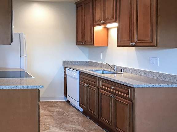 A kitchen with brown cabinets and a granite countertop.