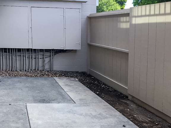 A concrete sidewalk leads to a white utility box.