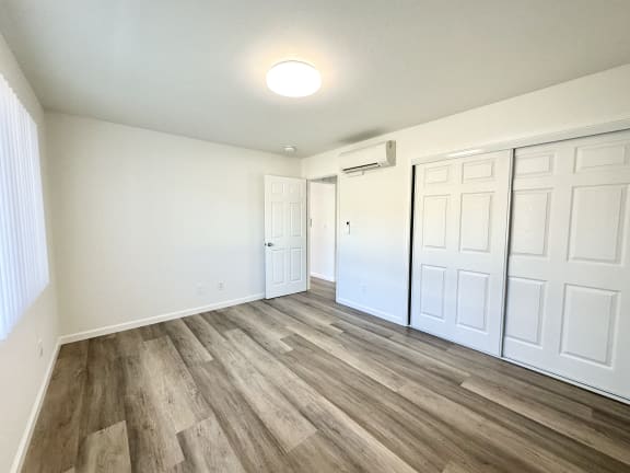 an empty room with white walls and wood floors