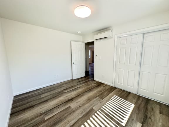 a bedroom with white walls and hardwood floors