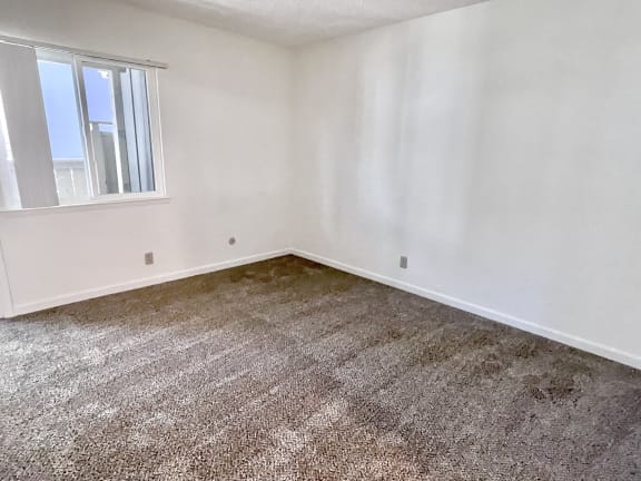 a bedroom with white walls and a window