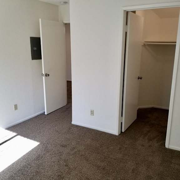 A room with a carpeted floor and two white doors.