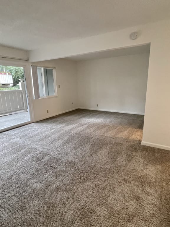 an empty living room with a sliding glass door and a balcony
