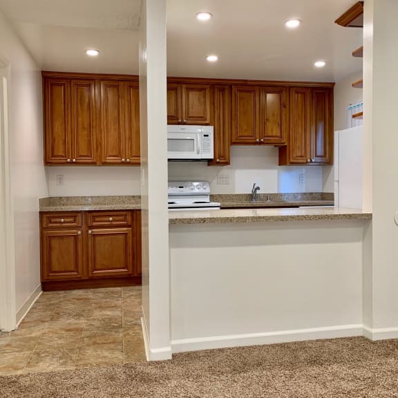 a kitchen with wood cabinets and tile flooring