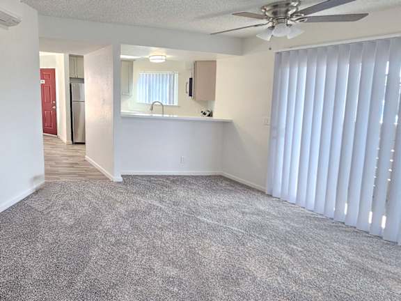 A room with a ceiling fan and carpeted floor.