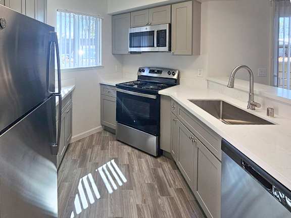 A modern kitchen with a stainless steel refrigerator, microwave, oven, and sink.