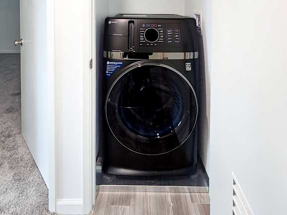 A black front loading washing machine in a small laundry room.