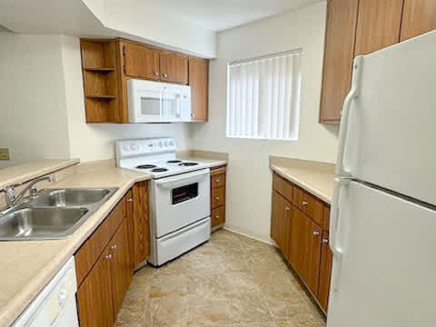 A kitchen with a white refrigerator, white oven, white microwave, and white sink.