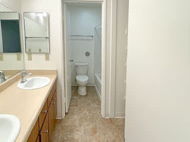 A bathroom with a sink, mirror, toilet and a door.