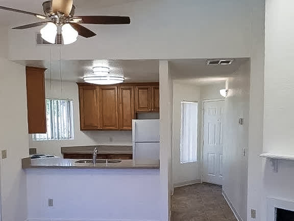 A kitchen with a white fridge and wooden cabinets.