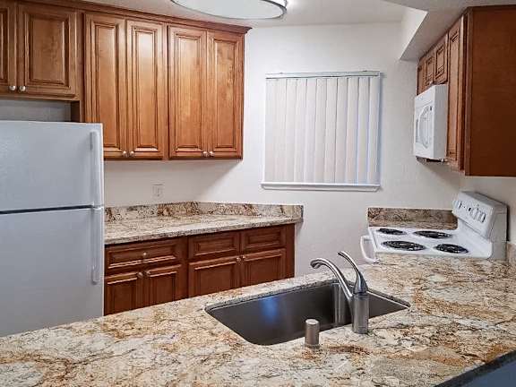 A kitchen with granite countertops and wooden cabinets.