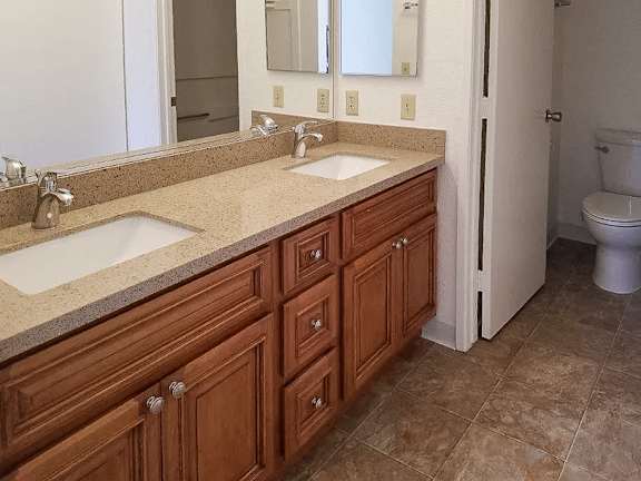 A bathroom with brown cabinets and a white sink.