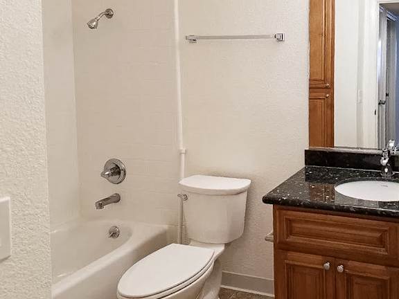 A white toilet sits next to a bathtub in a bathroom.