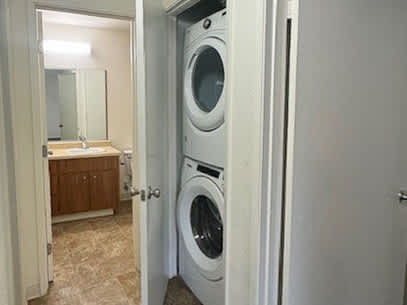 A white door is open to a bathroom with a washer and dryer in it.
