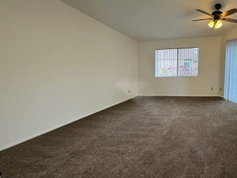 A room with a ceiling fan and carpeted floor.