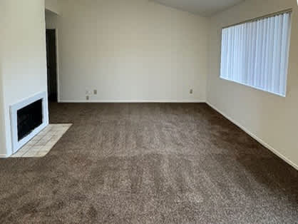 A room with a fireplace and carpeted floor.