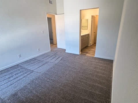 A room with a carpeted floor and a doorway leading to another room.