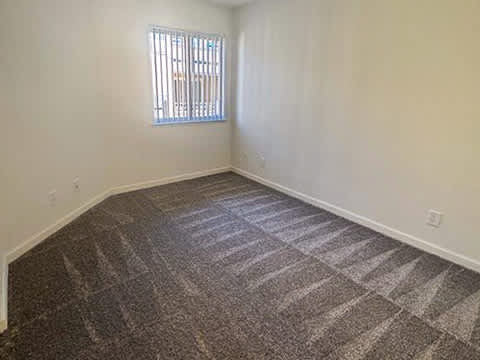 A room with a carpeted floor and a window.