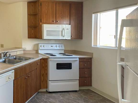 A kitchen with a white stove and wooden cabinets.