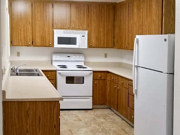 A kitchen with white appliances and wooden cabinets.